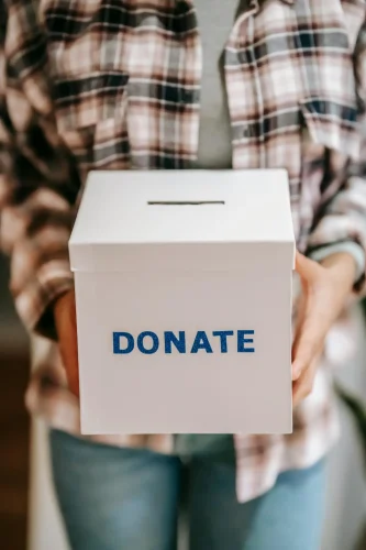 pexels-photo-6348119-6348119 Close-up of a person holding a 'donate' box, encouraging charity and support.